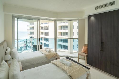 a bedroom with two beds and a large window at Grosvenor Beachfront Apartments Surfers Paradise in Gold Coast