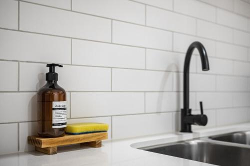 a bottle of alcohol sitting on a shelf next to a sink at Chic Flinders Park Getaway in Adelaide