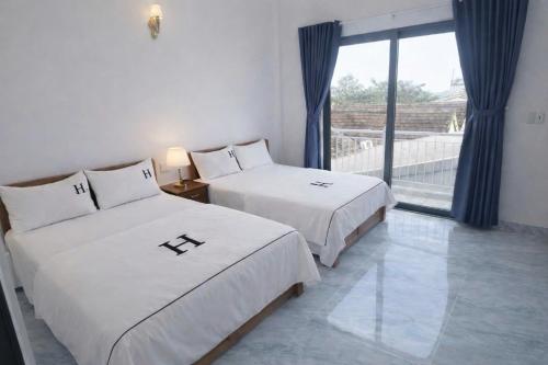 two beds in a room with a large window at Anh Dung Homestay in Ga Thừa Lưu