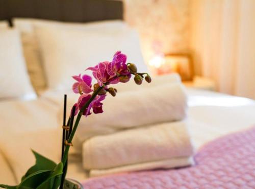 a purple flower in a vase on a table next to a bed at Franov Butique Residence in Kali