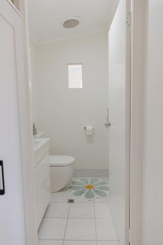 a white bathroom with a toilet and a sink at The Lake Guesthouse in Budgewoi