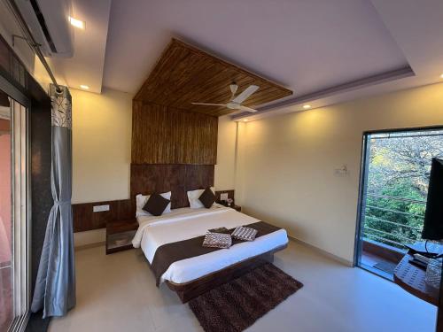 a bedroom with a bed and a large window at Hotel Mahabaleshwar Mount View in Mahabaleshwar