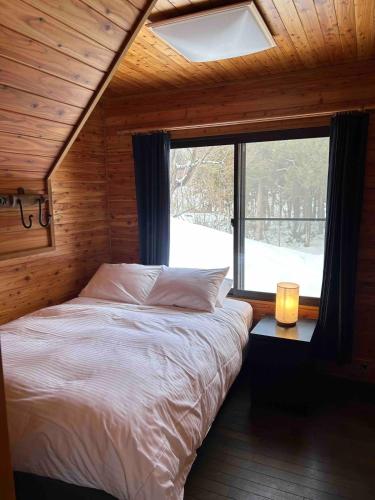a bedroom with a bed with a window and a candle at Kitakaze Chalet in Myoko
