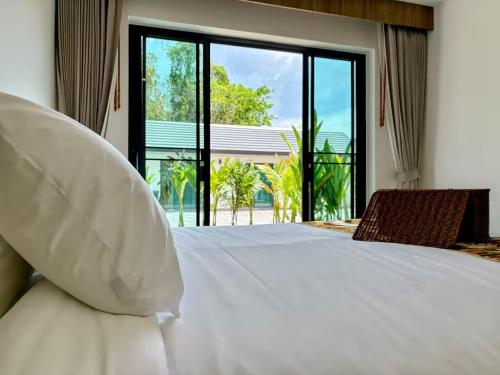 a bedroom with a white bed with a large window at Tiger on the Beach in Krabi