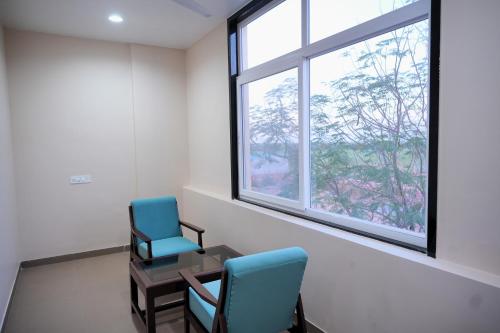 two chairs and a table in a room with a window at Sugan Hotel and Resort in Phalodi