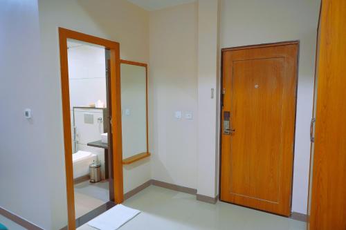 a bathroom with a wooden door and a mirror at Sugan Hotel and Resort in Phalodi