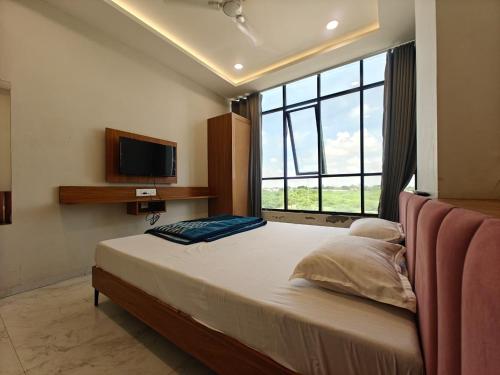 a bedroom with a large bed with a large window at Hotel Avenue Gest House in Dabhoi