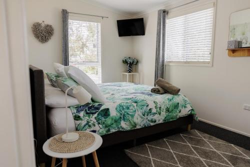 a small bedroom with a bed and a chair at The Lake Guesthouse in Budgewoi