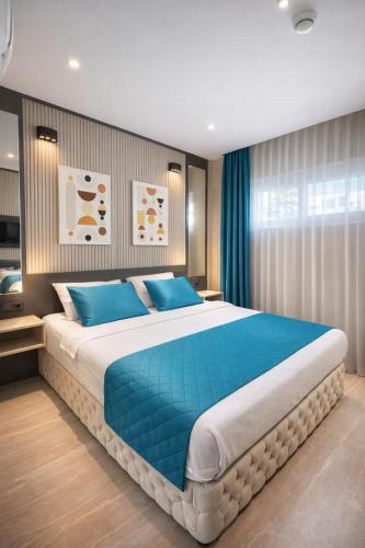 a bedroom with a large bed with blue pillows at Sky Luxe Hotel Konyaaltı in Antalya