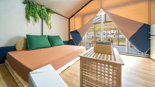 a room with a bed and a table and a window at Gapyeong Ddobagi Pet & Spa Glamping in Gapyeong