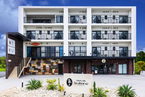 a large white building with a sign in front of it at Hotel & Villa Seahorse MIYAKOJIMA in Miyako-jima