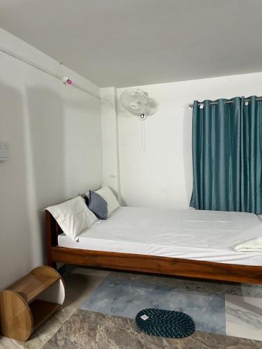 a small room with a bed and a blue curtain at Swagatom Homestay in Jorhat