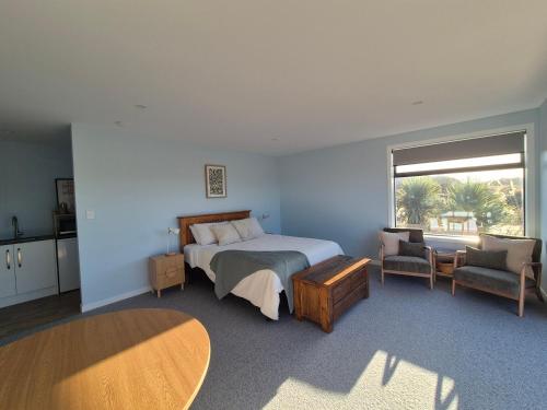 a bedroom with a bed and a table and a window at Accomodation at Curio in Curio Bay