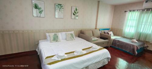 a bedroom with a large white bed and a couch at AnChanPoolvilla อัญชัญ พลูวิลล่า in Pak Johng