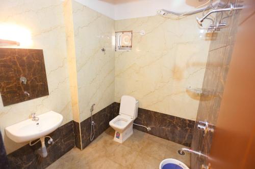 a bathroom with a white toilet and a sink at S V Grand Inn in Bangalore