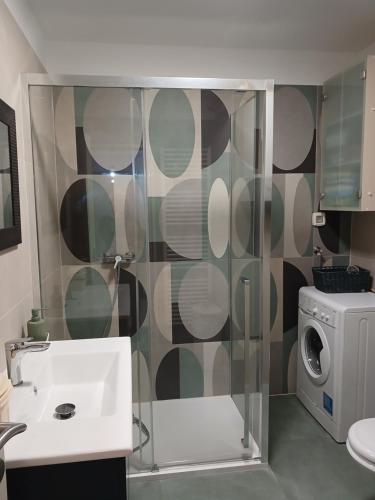 a bathroom with a shower with a sink and a washing machine at Lungo Mare in Pula