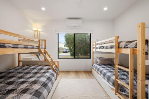 two bunk beds in a room with a window at The Cape House in Cape Woolamai