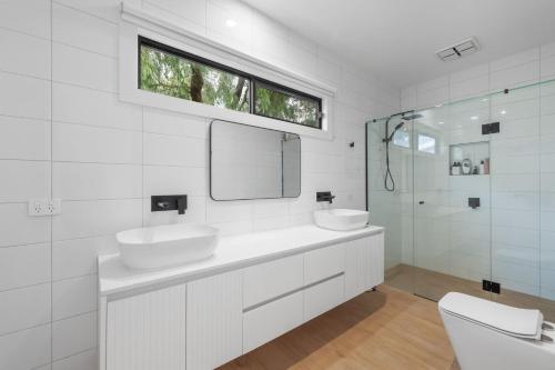a white bathroom with two sinks and a mirror at The Cape House in Cape Woolamai