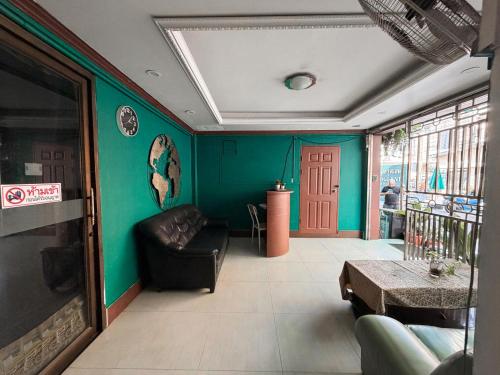 a living room with green walls and a black couch at Green Hotel in Pattaya South