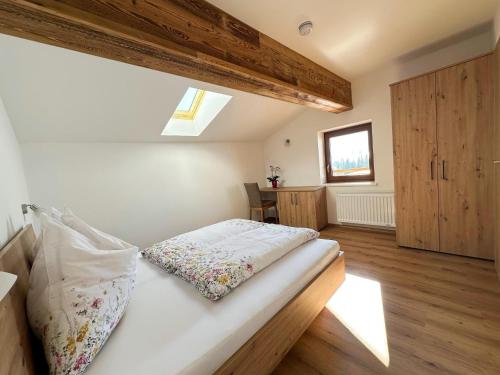 a bedroom with a bed with white sheets and wooden floors at Leogang apartment with mountain views in Leogang