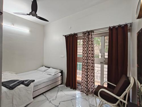 a bedroom with a bed and a chair and a window at Elegant 2 BHK Furnished flat without AC and with AC additional price in Belgaum