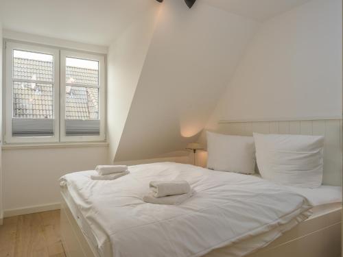 a white bed in a room with two towels on it at Dorfhüs 1 in Tinnum
