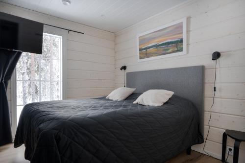 a bedroom with a bed with two pillows and a television at Villa Taalontuuli Aurora & Forest Views sleeps 10 in Kittilä