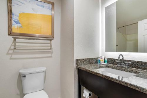 a bathroom with a toilet and a sink and a mirror at Comfort Inn Pensacola near NAS Corry Station in Pensacola