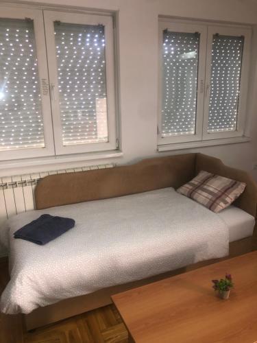 a bed in a room with two windows with lights at Guest House Sani in Skopje