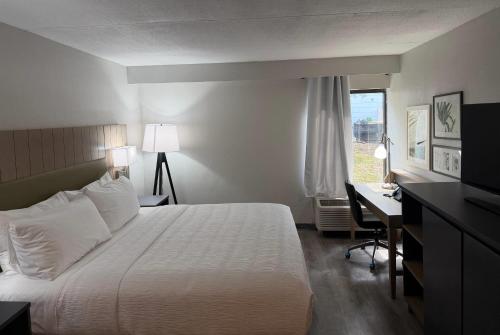 a hotel room with a bed and a desk and a window at Wingate by Wyndham Jacksonville FL in Jacksonville