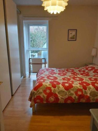 a bedroom with a bed with a flowered blanket and a window at COSY COTTAGE FOR SHARE , Private Double Room, Wifi, Parking, Garden in Edinburgh