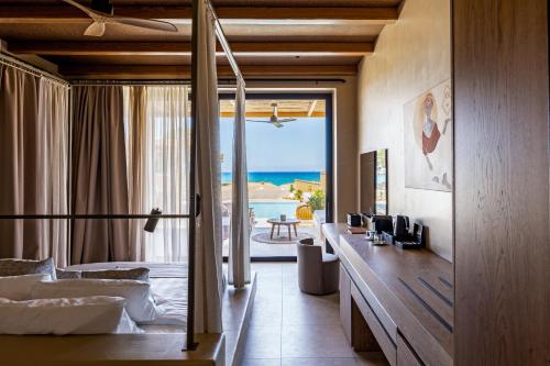 a hotel room with a bedroom with a view of the ocean at Unique Blue! Resort and Villas Adults Only in Karteros