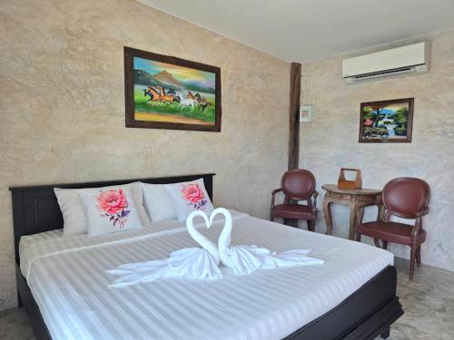 a hotel room with a bed with a white bedspread at ขวัญใจปราณ รีสอร์ท in Ban Pak Nam Pran