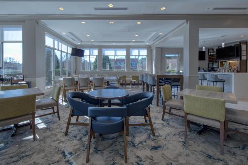 a dining room with tables and chairs and windows at Hilton Garden Inn Durham Southpoint in Durham