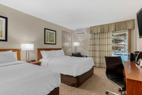 a hotel room with two beds and a desk at Clarion Hotel & Suites in Brandon