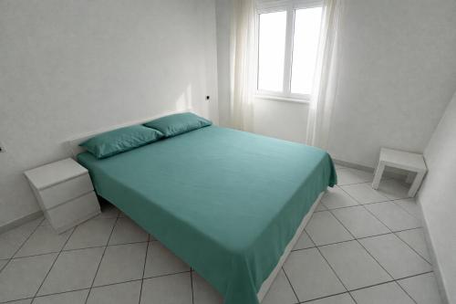 a bedroom with a bed with a green bedspread and a window at La casa di Lollo in Piombino