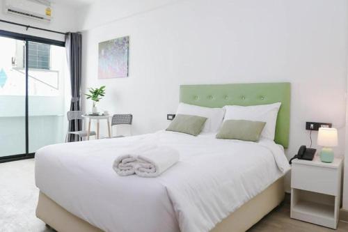 a bedroom with a large white bed with a green headboard at Chana Bangkok Hotel in Bangkok