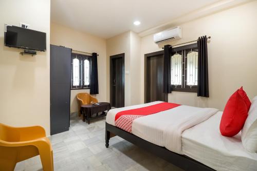 a bedroom with a bed with red pillows and a tv at Hotel O Annie in Rāmgarh