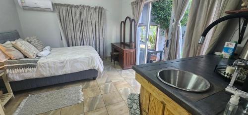 a bathroom with a sink and a bed in a room at Rose cottage Garden Suite in Pretoria