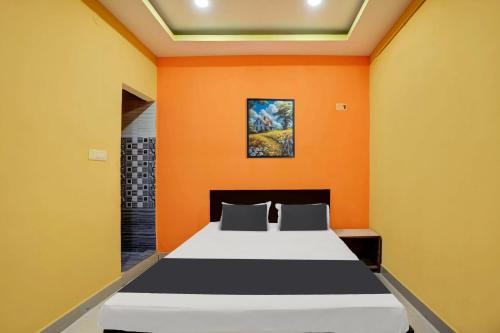 a bedroom with a bed with an orange wall at Hotel O DS TANDOORI in Bokāro