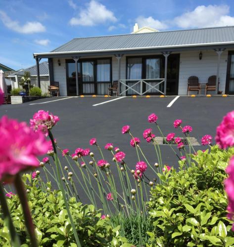a parking lot with pink flowers in front of a building at Lockwood Manor Motel in New Plymouth