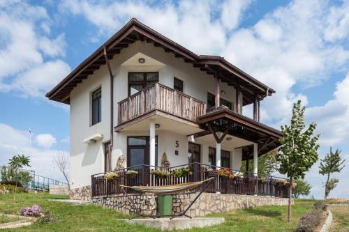 a large white house with a balcony at Balkana Village in Kalaydzhii