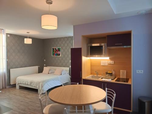 a room with a bed and a table and a kitchen at Appart'Hotel Parc Johan in Chauffailles