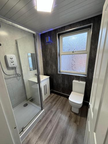 a bathroom with a shower and a toilet and a window at The Villas in Rock Ferry