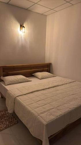 a bed in a bedroom with a light on the wall at Wilpattu Leisure Villa in Pahala Maragahawewa