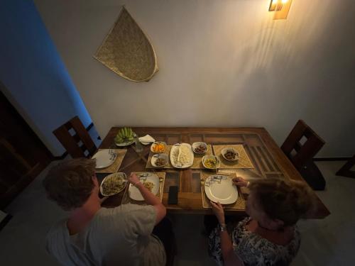 a group of people sitting around a table with food at Wilpattu Leisure Villa in Pahala Maragahawewa