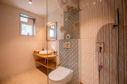 a bathroom with a toilet and a glass shower at Staymaster Solintra - Serviced Apartment - Pool in Nerul