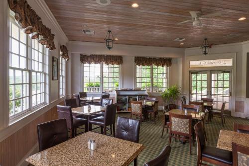 a restaurant with tables and chairs and windows at Cypress Bend Resort, a Wyndham Hotel in Many