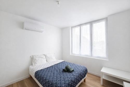 a white bedroom with a bed and a window at Le Cocon d'Ezy in Ézy-sur-Eure