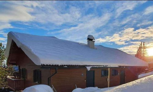 a barn covered in snow with the sun in the background at Almzeit Klippitz in Klippitztorl